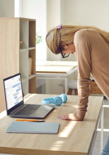 Woman leaning on desk, dealing with low back pain